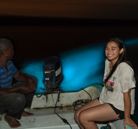 Sarah poses in front of the spectacular, glowing boat wake as Clifford makes a slow turn through the bioluminescent lagoon.